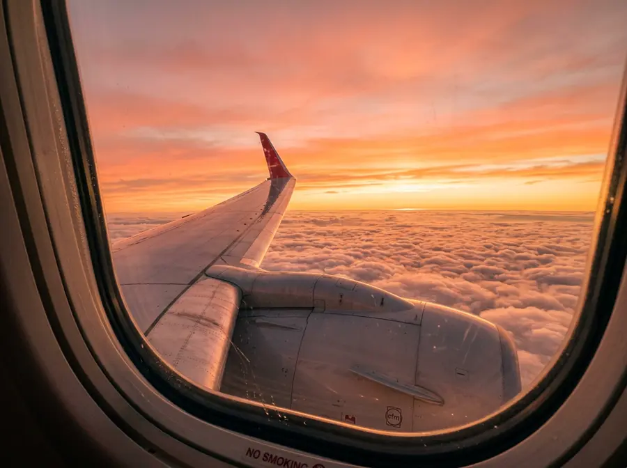 Airplane wing above the clouds at sunset